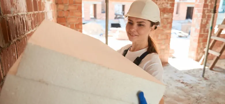 Žena drží desky z expandovaného polystyrenu na staveništi.