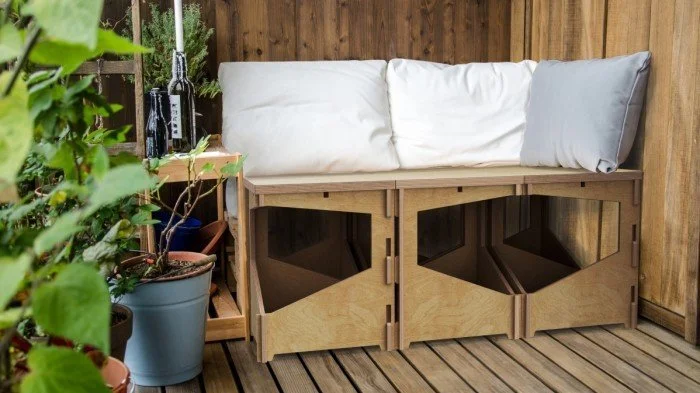 Dřevěná lavička s polštáři na dřevěném balkóně panelového domu.
