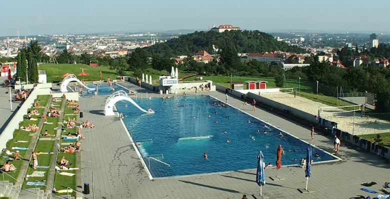 Venkovní bazén na kopci s plaveckou dráhou a lehátky.