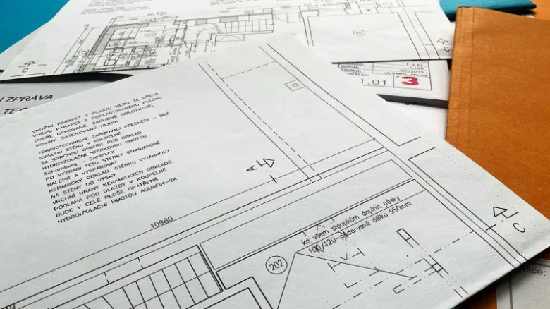 Architektonické plány a stavební dokumentace na stole.