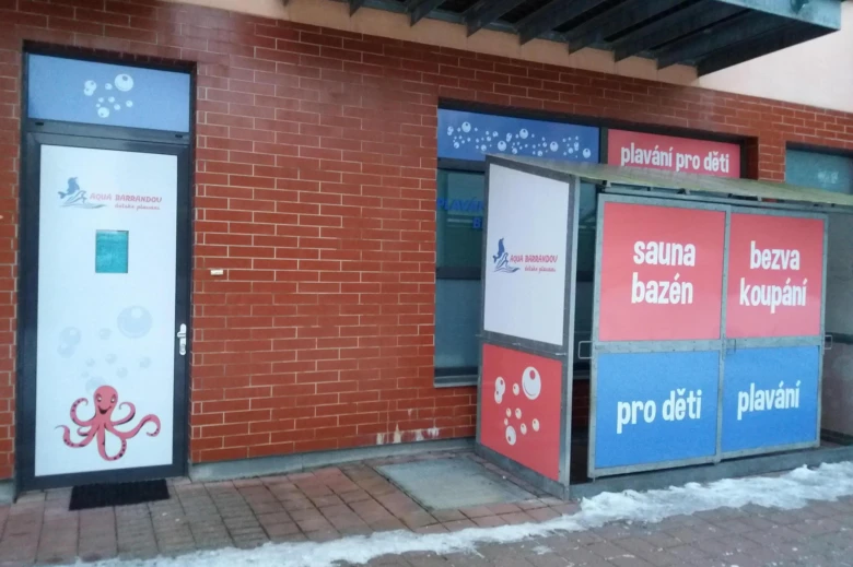 Vstup do plaveckého bazénu v Barrandově s reklamními tabulemi.