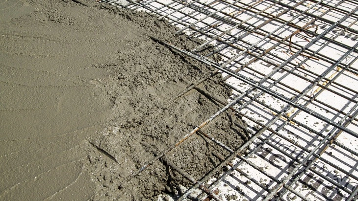 Čerstvý beton nalitý na ocelovou výztužnou mřížku.