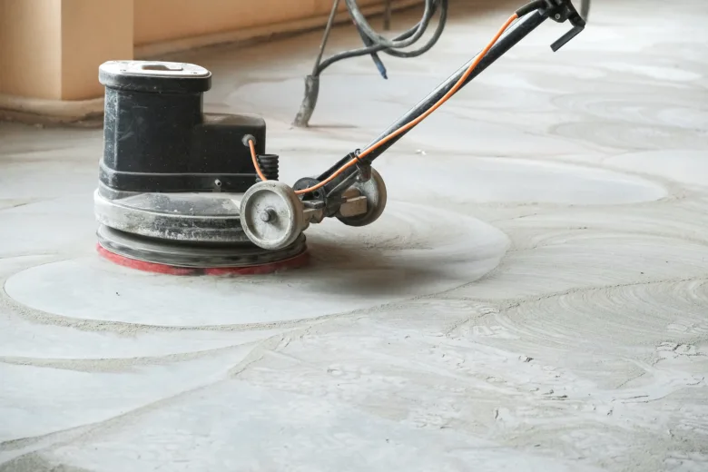 Černý stroj na leštění betonové podlahy v akci.