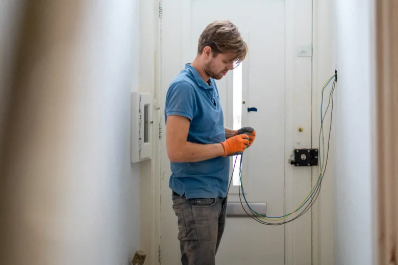 Elektrikář opravuje instalaci v domácnosti s dráty.