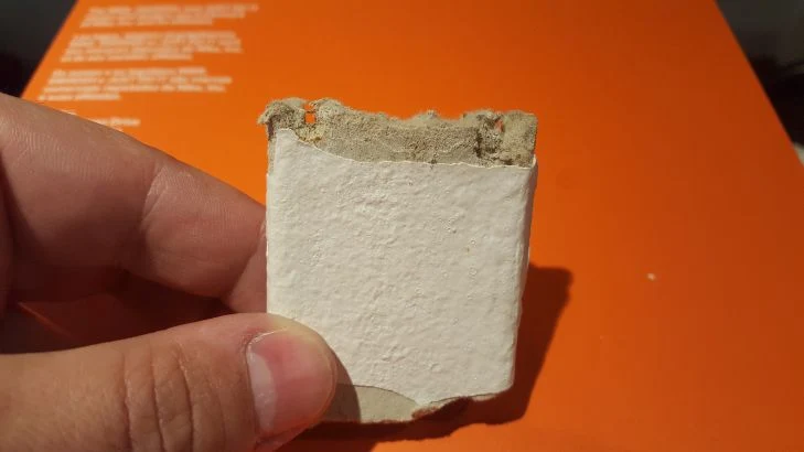 Rozbitý kus bílého azbestocementu s viditelnou vláknitou vrstvou.