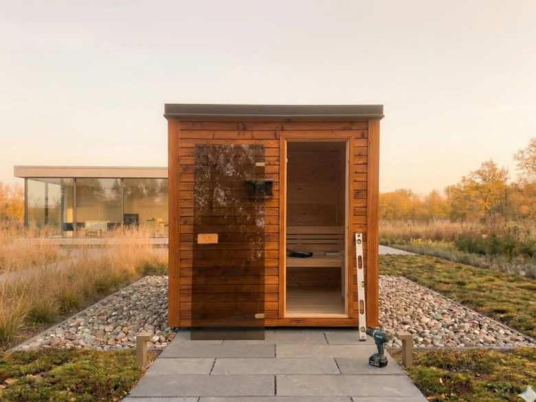 Dřevěná finská sauna postavená svépomocí s nástroji uvnitř.
