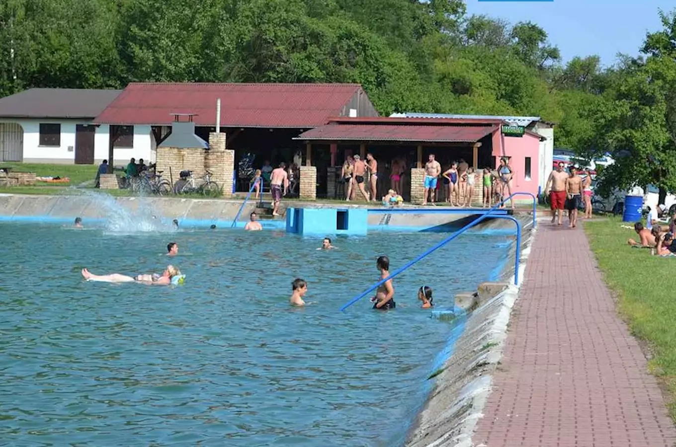 Venkovní bazén ve Všejanech s plavci u budov