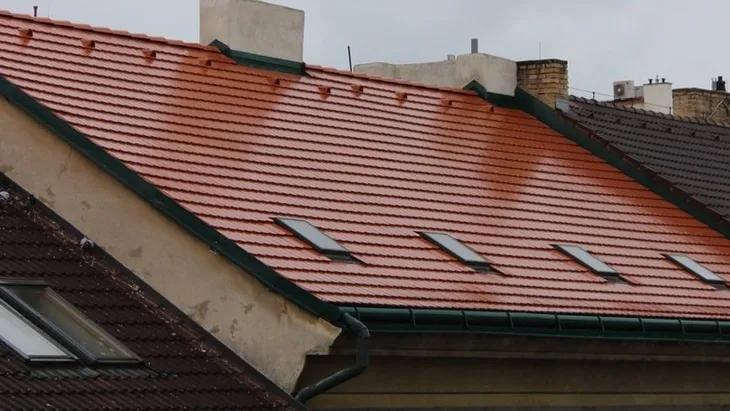 Červené keramické střešní tašky s okny na skloněné střechu.