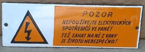 Varovný štítek upozorňuje na nebezpečí elektrického proudu v koupelně.