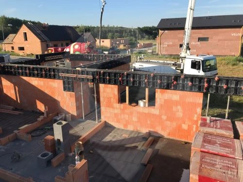Armování a bednění betonového věnce na stavbě s cihlovými zdmi.