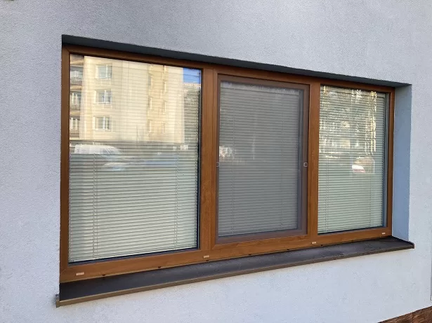 Moderní okno s roletami nainstalované v exteriéru budovy.