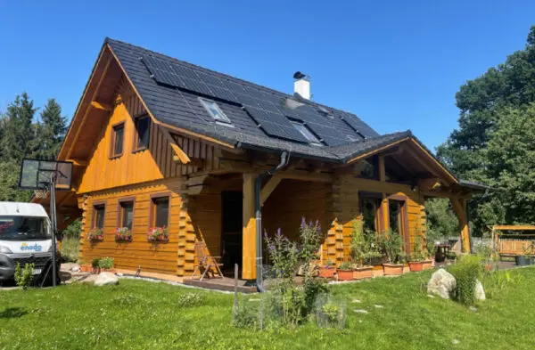 Dřevěný dům s fotovoltaickými panely na střeše.