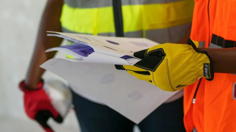 Stavebníci v ochranném obleku prohlížejí dokumentaci staveb.
