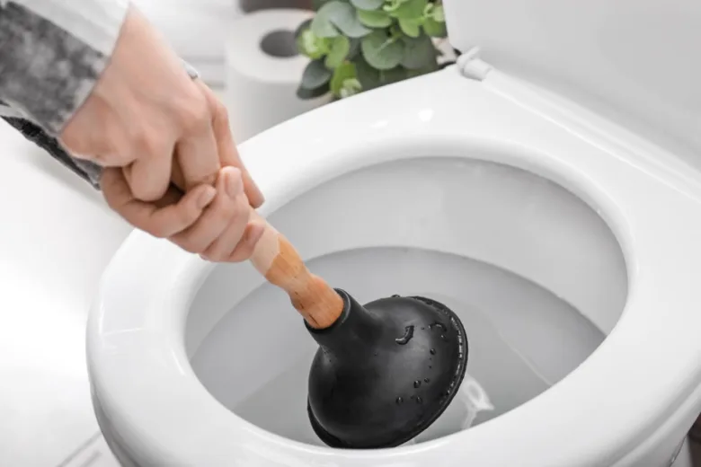 Ruka drží hadicovou pumpu v záchodové misě pro odcpování.