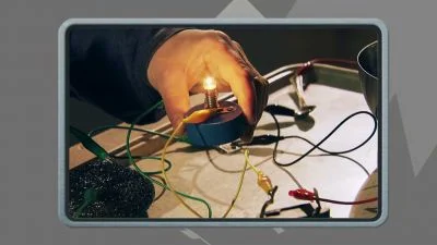 Ruka drží zapálenou žárovku s propojenými elektrickými vodiči.
