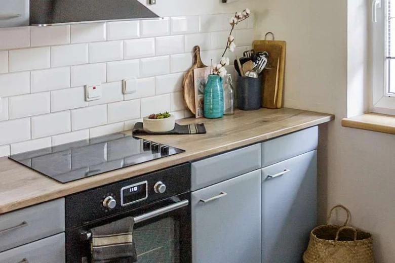 Moderní kuchyňská linka po renovaci s dřevěnou pracovní deskou.