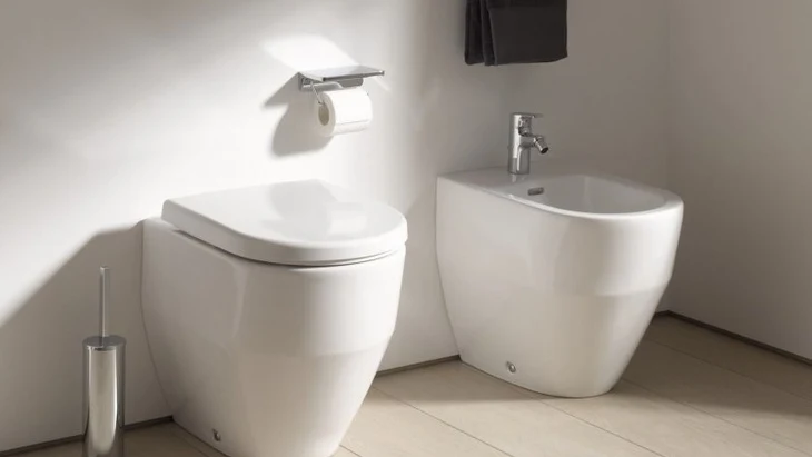 Moderní koupelna s toaletou a vedlejším umyvadlem pro hygienu.