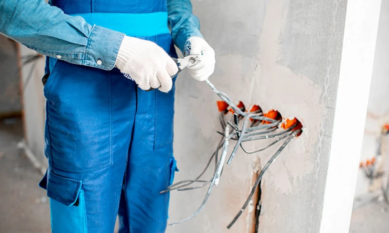 Elektrikář pracuje na instalaci zásuvek a vypínačů ve zdi.