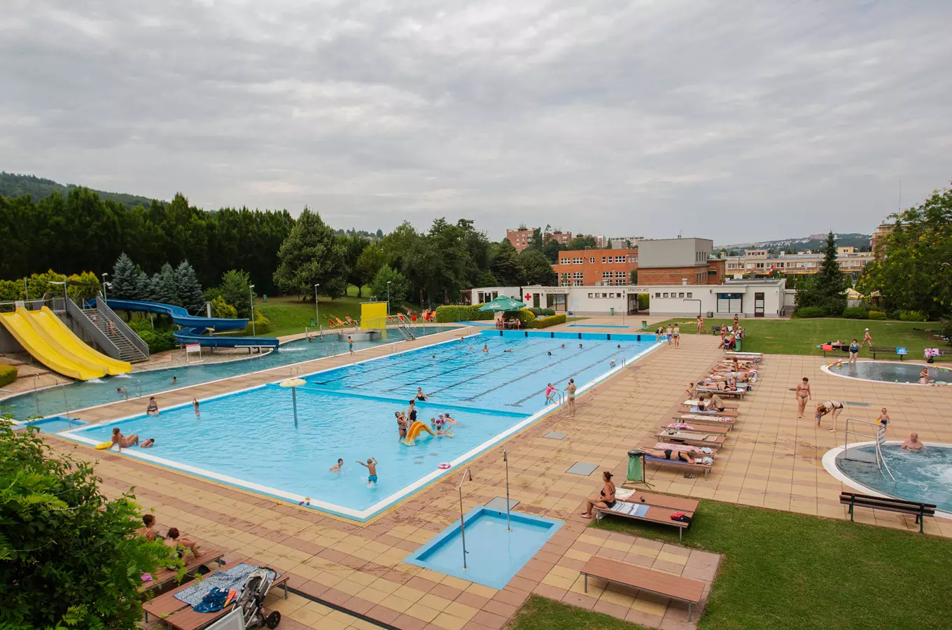 Venkovní plavecký bazén s skluzavkami a lehátky.