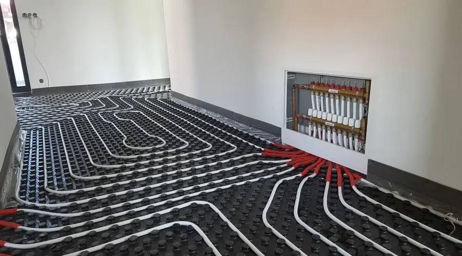 Instalace potrubí podlahového topení s rozdělovačem v místnosti.