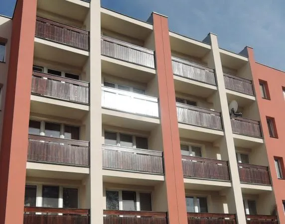 Vícepodlažní dům s dřevěnými balkony po rekonstrukci.