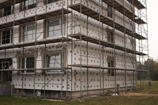 Stavební práce na fasádě při zateplování budovy s izolačními deskami.