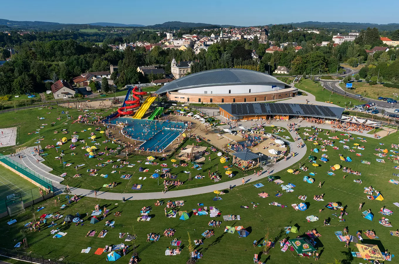Vzdušný pohled na venkovní koupaliště v Turnově s bazénem a skluzavkami.