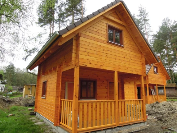 Dřevěná chata s podkrovím a malé dřevostavby v přírodě.
