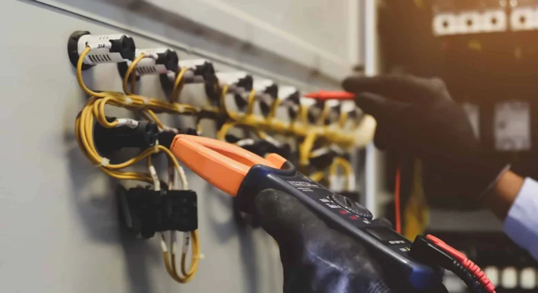 Elektrikář měří napětí v rozvaděči pomocí multimetru.