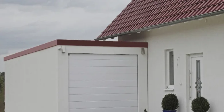 Bílá garáž připojená k domu s červenou střechou a okny.