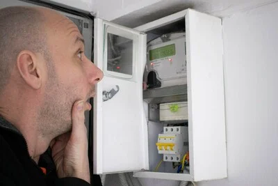 Muž čte stav elektroměru v rozvaděči.