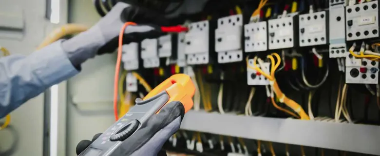 Elektrikář měří napětí v rozvaděči pomocí multimetru.