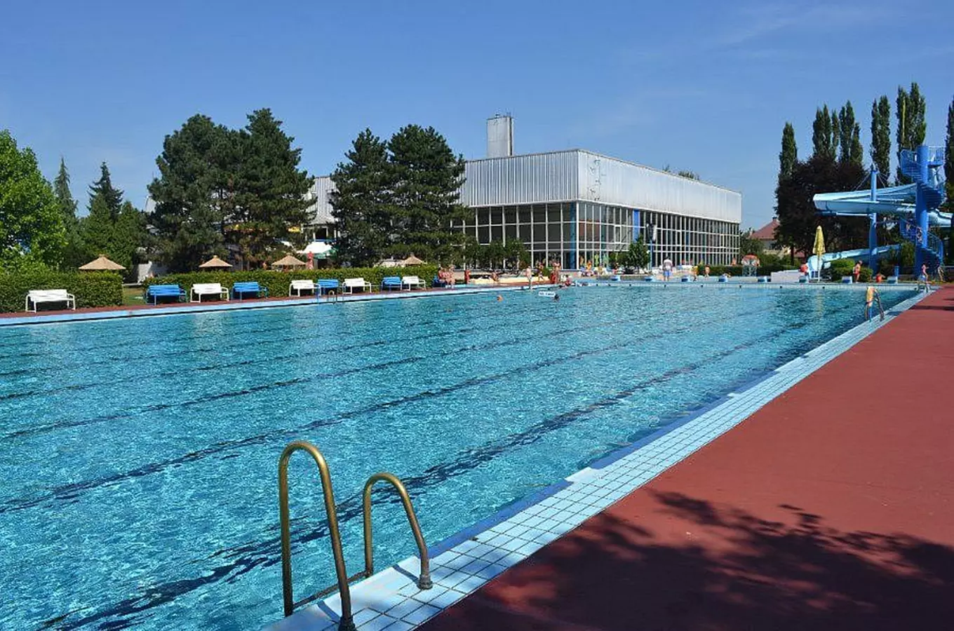 Venkovní bazén v novém jičíně s lehátky a vodními skluzavkami.