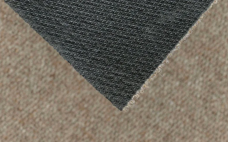 Detail tmavého koberce s texturou na světlém podlaze
