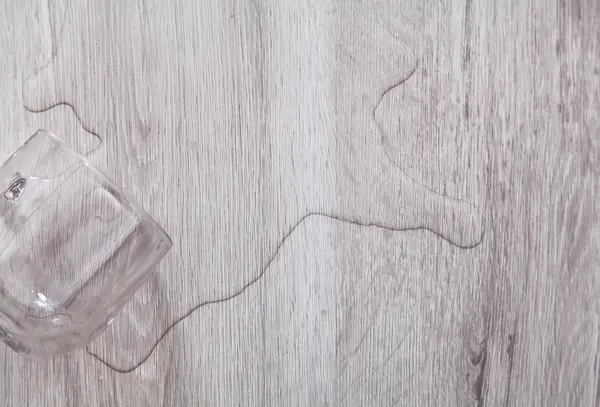 Voda z hrnku rozlitá na vinylové podlaze.