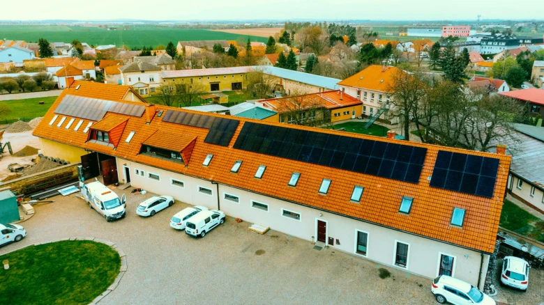 Vzdušný pohled na dům s instalovanými solárními panely na střeše.