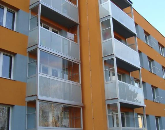 Moderní balkony s výplněmi z bílých oken po rekonstrukci.