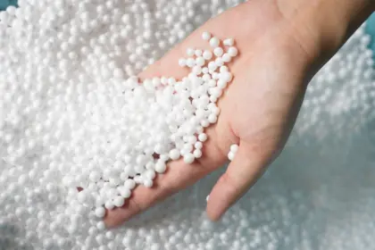 Ruka drží bílé kuličky expandovaného polystyrenu.