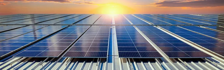 Fotovoltaické panely namontované na střechu při západu slunce.