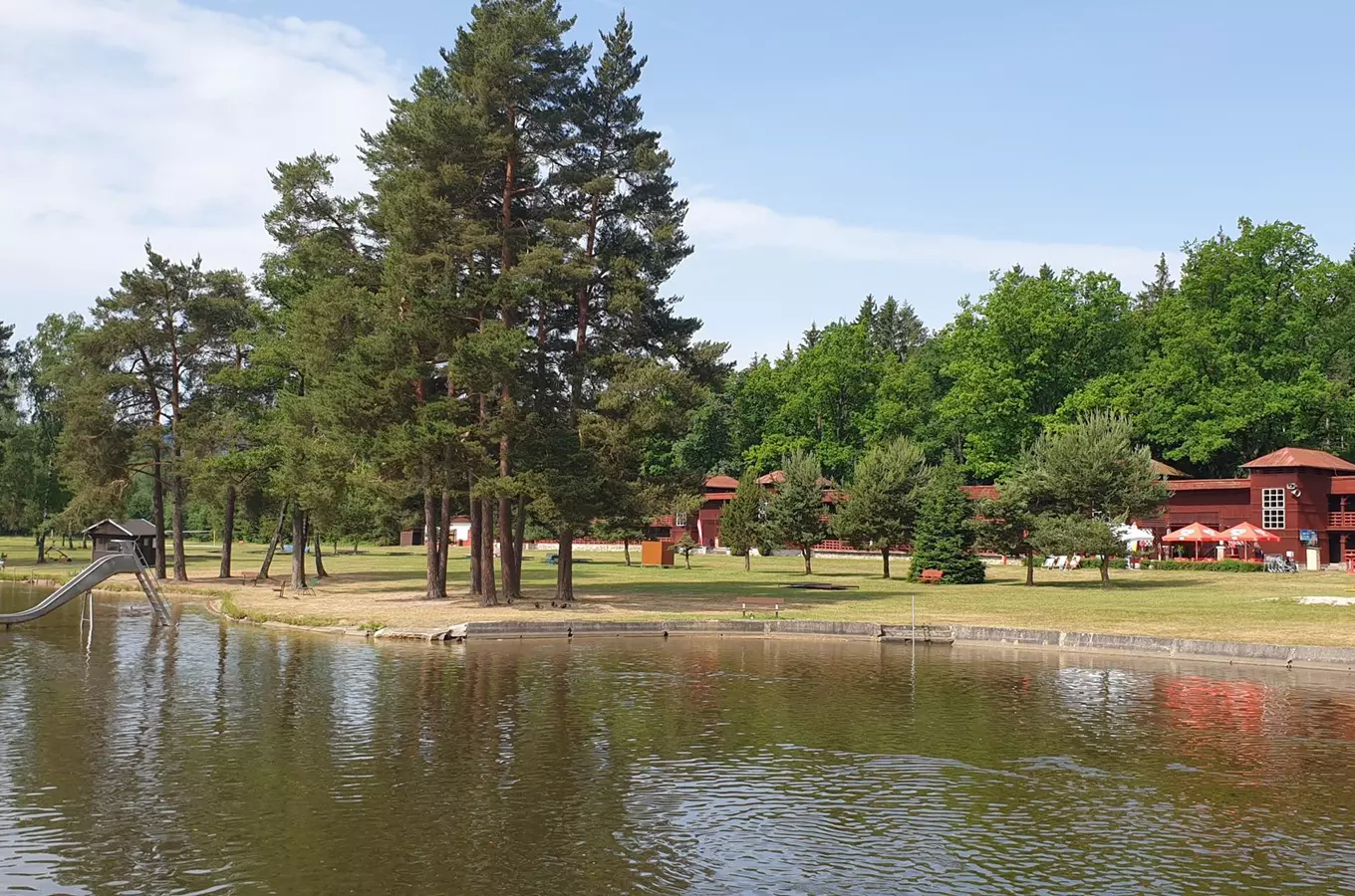 Koupaliště Babylon Domažlice s bazénem, stromy a budovami.