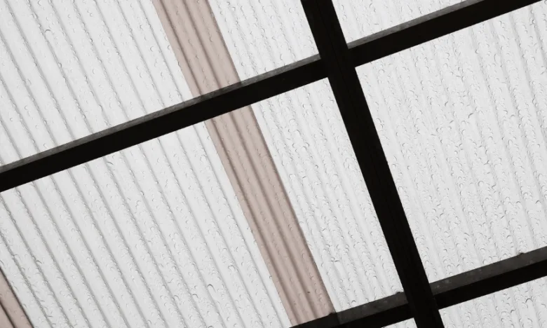 Střecha z průhledného oplechování s kapkami deště na povrchu.