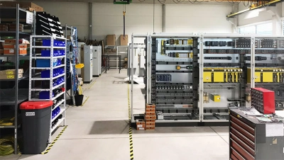 Výroba elektrorozvaděčů na výrobní lince s komponenty v regálech.