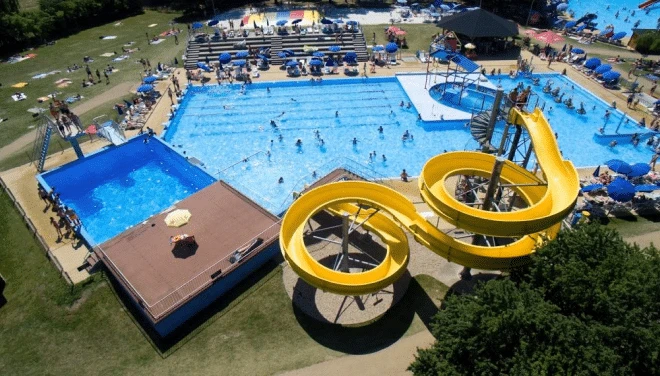 Vzdušný pohled na bazénový komplex s žlutými skluzavkami.