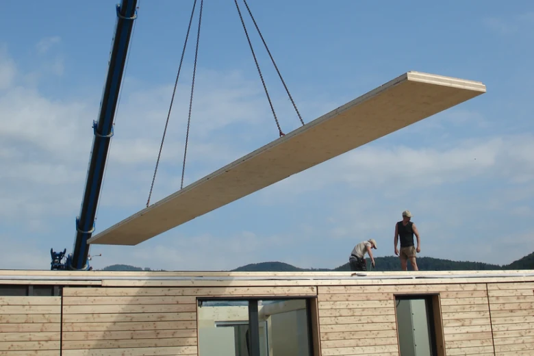 Výstavba z CLT: jeřáb zvedá dřevěný panel na střechu.