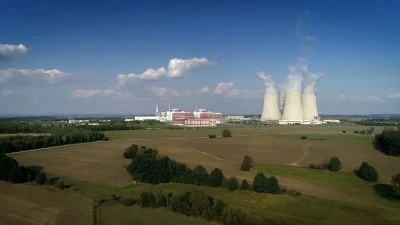 Jaderná elektrárna s chladiči v zeleném krajině.