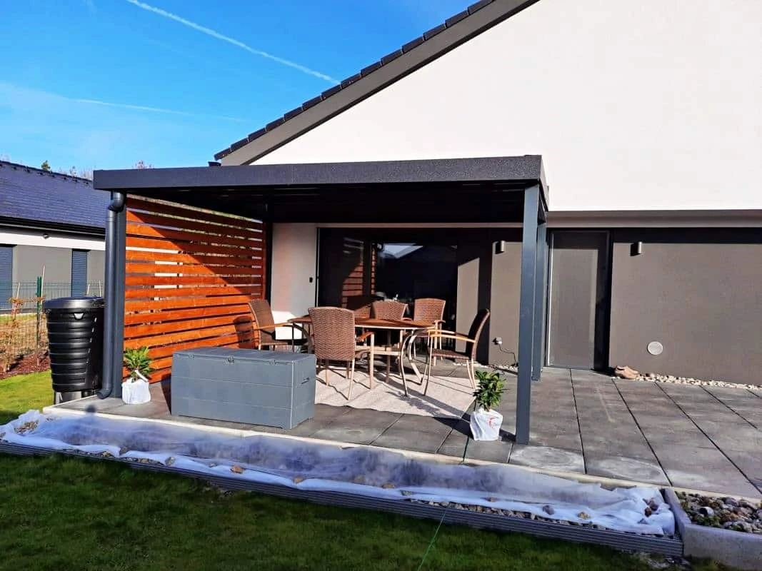 Dřevěná pergola s dřevěnou stěnou na zahradním terasu.