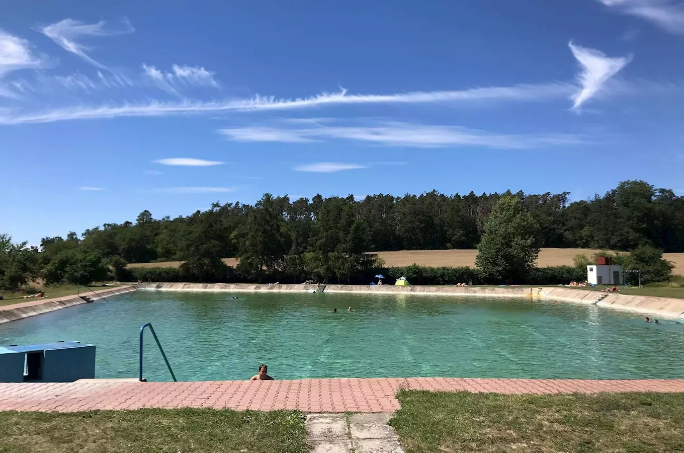 Venkovní plavecký bazén ve Všejanech s lidmi v vodě.
