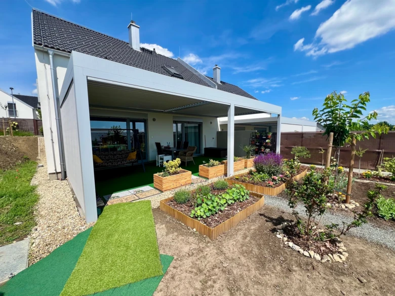 Dokončená bílá pergola s dřevěnými kvetinovými bednami v zahradě.