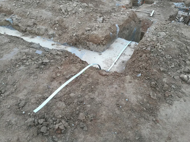 Bílý vodič uzemnění položený v zákopu pro elektroinstalaci.