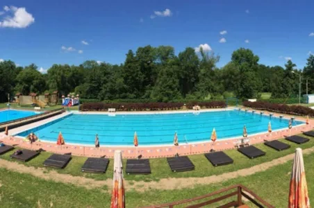 Venkovní bazén s lehátky pod modrou oblohou v Olomouci nebo na Moravě.